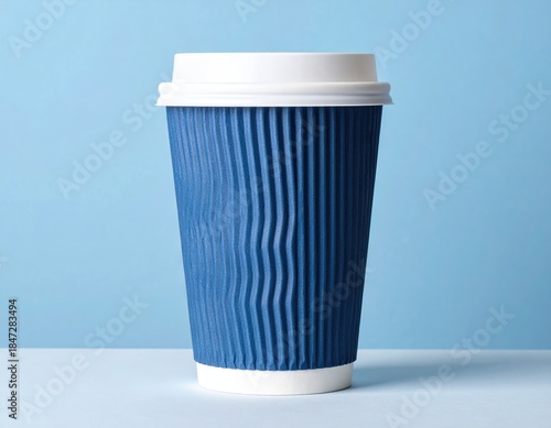 Tall blue corrugated paper cup with white lid against a light blue backdrop