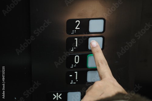 Finger presses elevator button to go to first floor