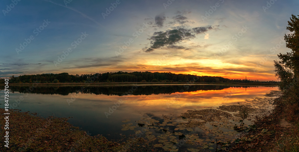 Fototapeta premium Beautiful summer sunset and colorful sky over the lake. Clouds are reflected in the calm water. Beauty in this world