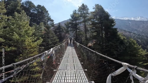 Rear view of tourist walking on the suspension bridge for crossing Dudh Koshi river in Sagarmatha national park of Nepal.