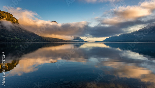 serene mountain lake with reflections and cloudy sky during sunset or sunrise.