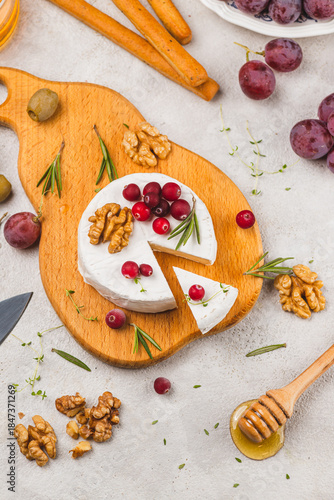 Brie cheese on a board with walnuts, honey and berries