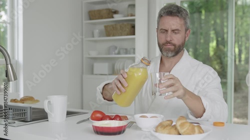 Morning breakfast with juice. Healthy breakfast in morning. Mature man eating breakfast in kitchen, healthy lifestyle. Hispanic man having home breakfast. Home morning food. Man eat food