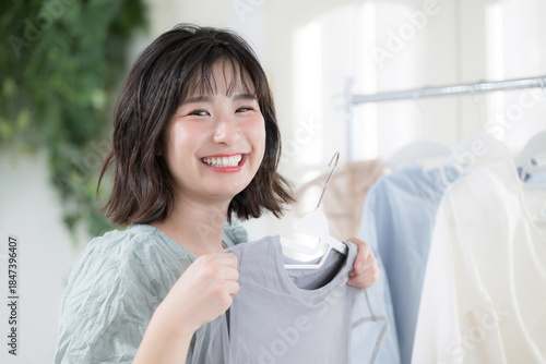Cuadro en lienzo 洋服を手に取り笑顔で選ぶ若い女性のガーリーなファッションライフスタイル　カメラ目線のクローズアップ