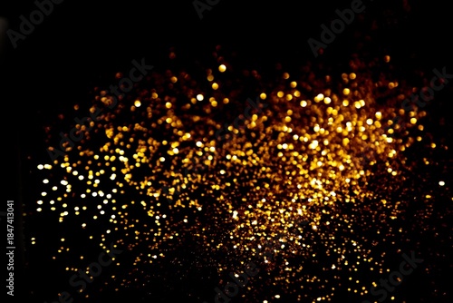Dense golden glitter cloud across dark background, dramatic sparkling dust texture for luxury celebration scenes, party flyers, festive banners, social media graphics and digital designs

