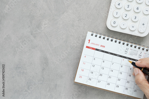 Foto Hand writing on 2026 calendar with calculator on grey desk