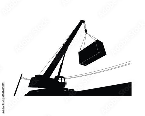 Construction crane lifting a heavy load in silhouette against a white sky