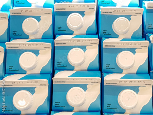 Rows of blue milk cartons with white labels, showcasing a clean and organized display in a grocery store. Ideal for food and beverage industry concepts.
