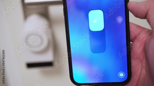 Close up of a man using a smartphone app to unlock a smart door lock remotely.