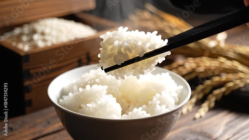 Steaming hot white rice bowl with chopsticks on rustic wooden table fresh grain background food preparation