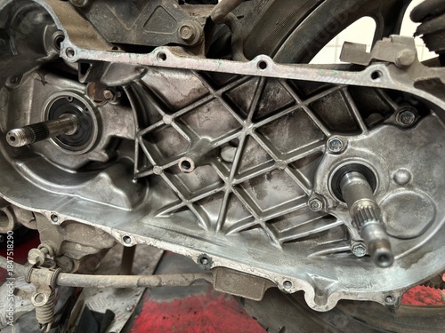 Close-up detail of a disassembled motorcycle transmission casing with visible gears and mechanical parts, showcasing maintenance and repair process in a workshop
