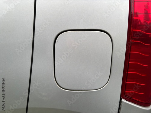 Close-up of silver car fuel tank cap door with clean surface and modern automotive detail
