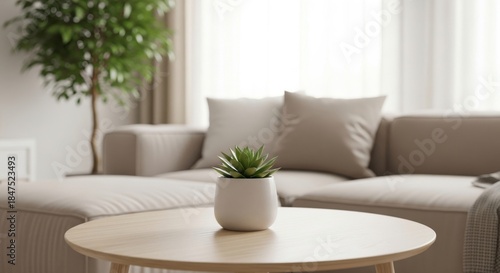 Cozy living room interior with light brown wooden coffee table. Small succulent plant sits on table. Beige sofa blurred in background