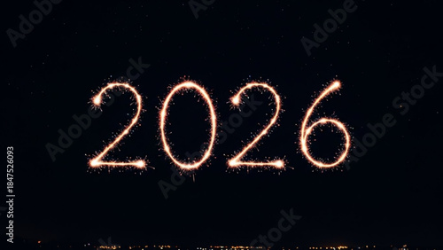 Glowing sparklers forming the year 2026 against a dark night sky with city lights in the background