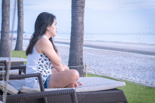 Asian woman relaxing on beach chair enjoying beautiful seaside view during summer vacation