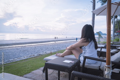 Asian woman relaxing on beach chair enjoying beautiful seaside view during summer vacation