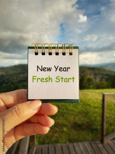 Note with “New Year Fresh Start” held outdoors, representing new beginnings, renewal, and goal setting.