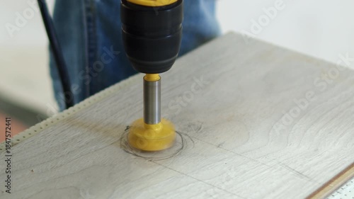 Worker Using Drill to Make Round Hole in Wooden Surface