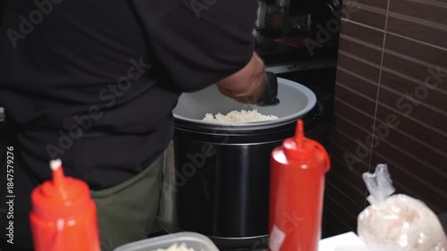 Close-up of a sushi chef wearing gloves taking sushi rice from a large bowl in the kitchen of a Japanese restaurant. The sushi cooking process.