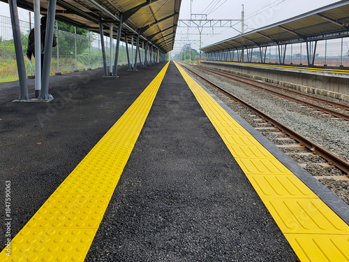 Empty train station platform with yellow tactile warning lines.