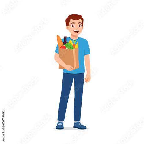 Young man smiling holding a grocery paper bag full of fresh food items after shopping happy mood