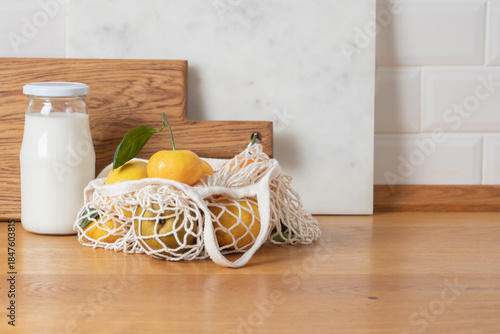 Zero waste kitchen concept with wooden cutting board, glass jar and eco mesh bag on wooden table in bright minimalist home interior
