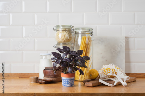 Zero waste kitchen concept with wooden utensils, glass jars and eco mesh bag on wooden table in bright minimalist home interior