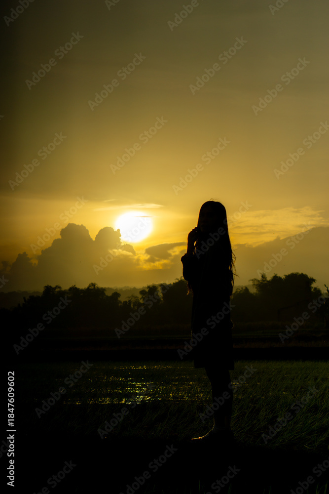 Fototapeta premium Silhouette of an Asian woman at sunset. Illustration of a lonely woman, an introverted woman. World Introvert Day.