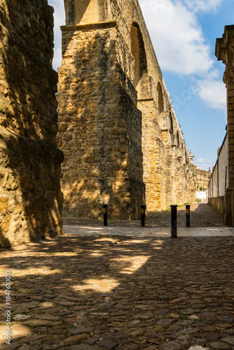Historic Stone Aqueduct and Cobblestone Street in European Old Town