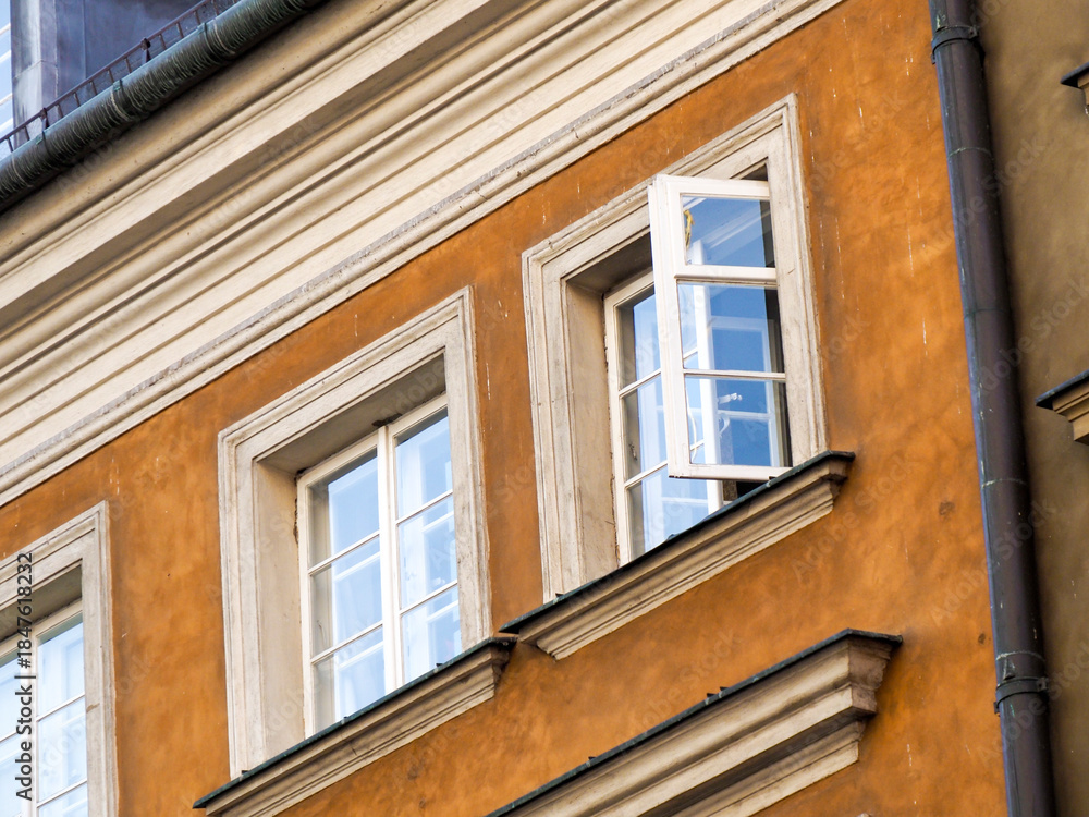 Obraz premium Close-up of the facade of an orange and yellow historic tenement house with white window frames.