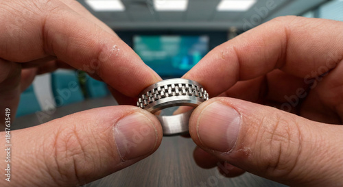 Close up of hands playing with metal fidget ring during office meeting for stress relief.