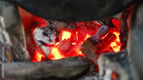 Glowing charcoal embers burning in a traditional clay stove close up