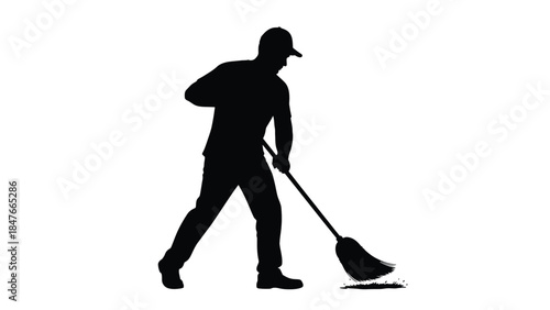 Silhouette of a worker wearing a cap sweeping debris with a large broom