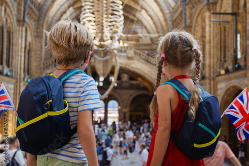 Siblings tourists fascinated by large whale skeleton in museum