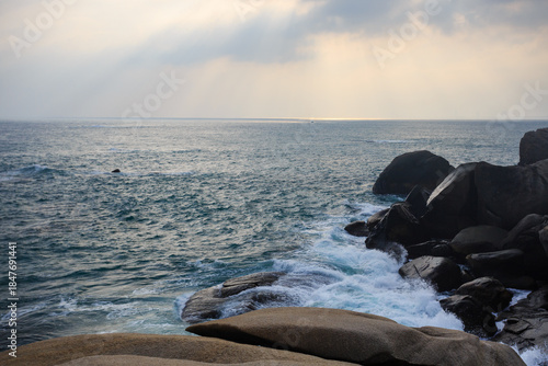 The scenery of Stone Park in Hainan, China, features emerald-green seawater crashing against the rocks, creating beautiful waves.