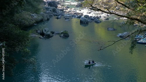 Takachiho Gorge in Takachiho, Miyazaki, Kyushu, Japan, People rowing boats on calm river surrounded by trees and rocks