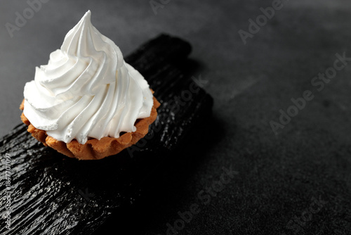 A sand basket with protein cream stands on a black wooden board on a gray background