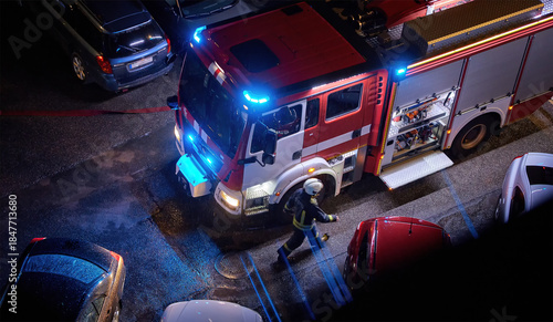 Fire truck at an urban emergency scene at night. Firefighter on duty. Concept of firefighting, emergency response, public safety, insurance, rescue services, city infrastructure, and crisis management