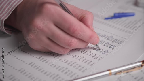 Hand Checking YearEnd Figures On Printout, Accountant Reconciling Ledgers And Marking Adjustments With Pen, Gold And Blue Pens On Desk, Quiet Focus During Close Process