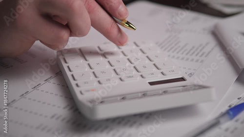 Caucasian Accountant Tapping Calculator Keys Over Financial Sheets With Pen Nearby, Closeup Of Hand Computing Totals And Reconciling Columns, Focused Desktop Workflow In Accounting Setting