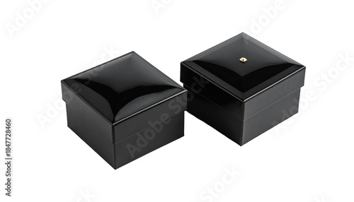 Two square black boxes with shiny lids, one with a small gold-colored dot on top, against a black background