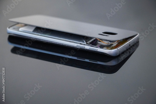 Damaged mobile phone on a black background. Swollen lithium ion polymer battery inside a smartphone.