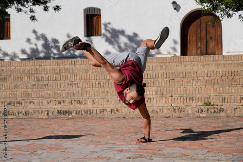 Man breakdancing a handstand freeze on urban bricks