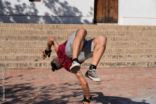 Man breakdancing a handstand freeze on urban bricks