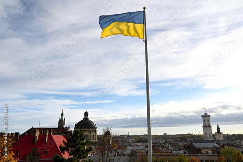Ukrainian flag flutters in the wind on the background the city of Lviv, Ukraine. Lviv panorama.