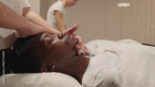 African american woman receiving relaxing facial massage at spa