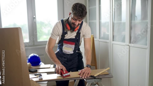 A young man working with wood in a modern workshop, focused on crafting and woodworking.