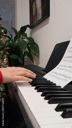 Elegant hands of pianist playing piano near Christmas tree during festive concert