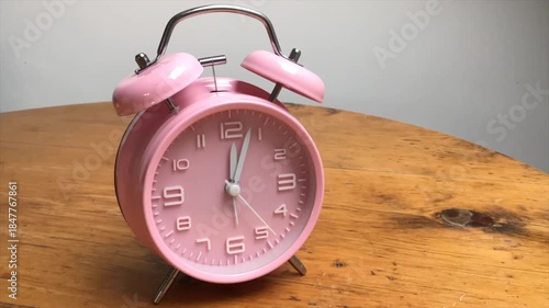 Pink alarm  clock running backwards. Concept turn back time