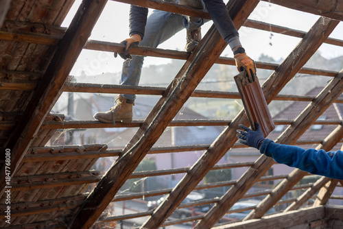 Teamwork of guys dismantling and reconstructing an old house and roof